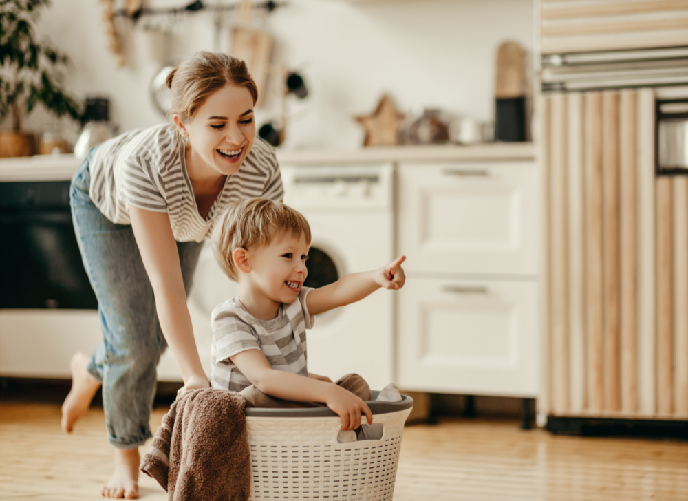 Happy family mother housewife and child son in laundry with washing machine