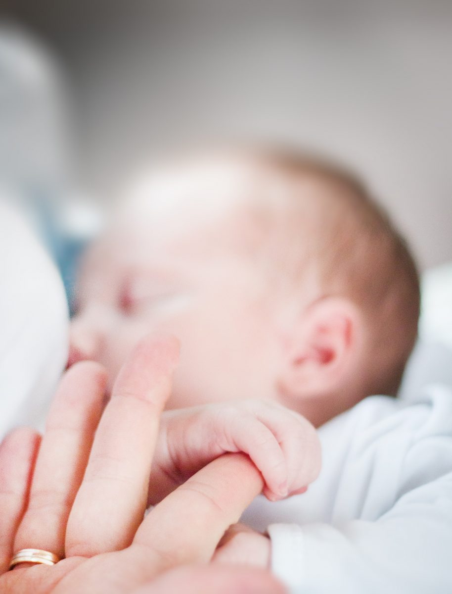 Baby sleeping while holding mom's finger