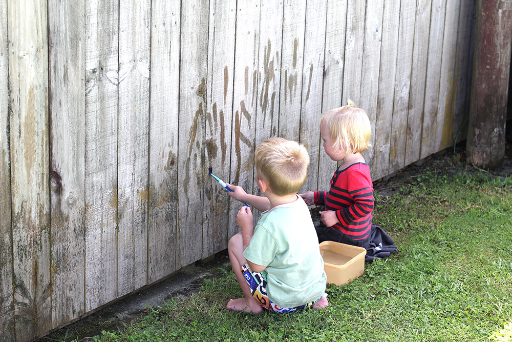 toddlers painting fence