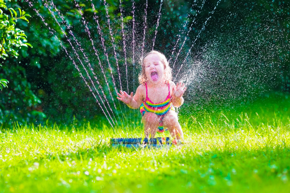 little girl playing in water sprinkler