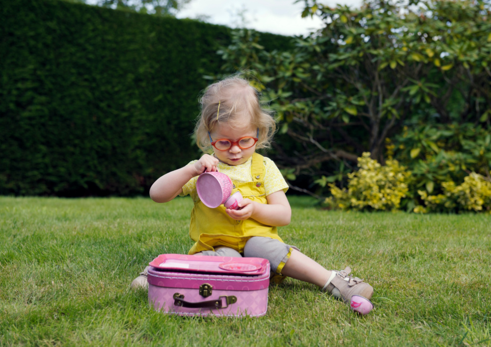 toddler girl playing with tea set outside