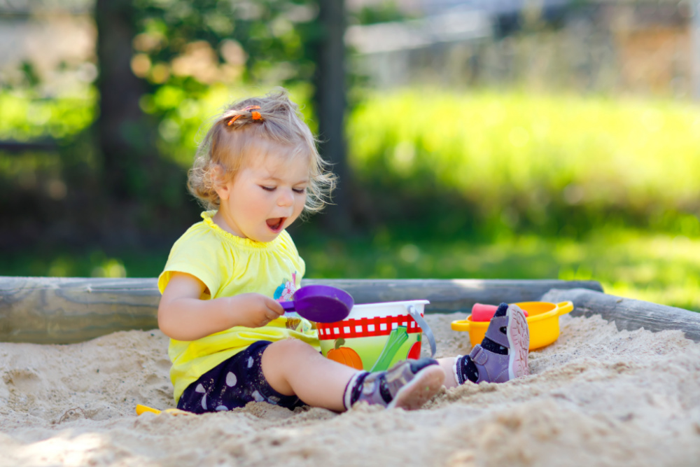 toddler girl playing in sandpit