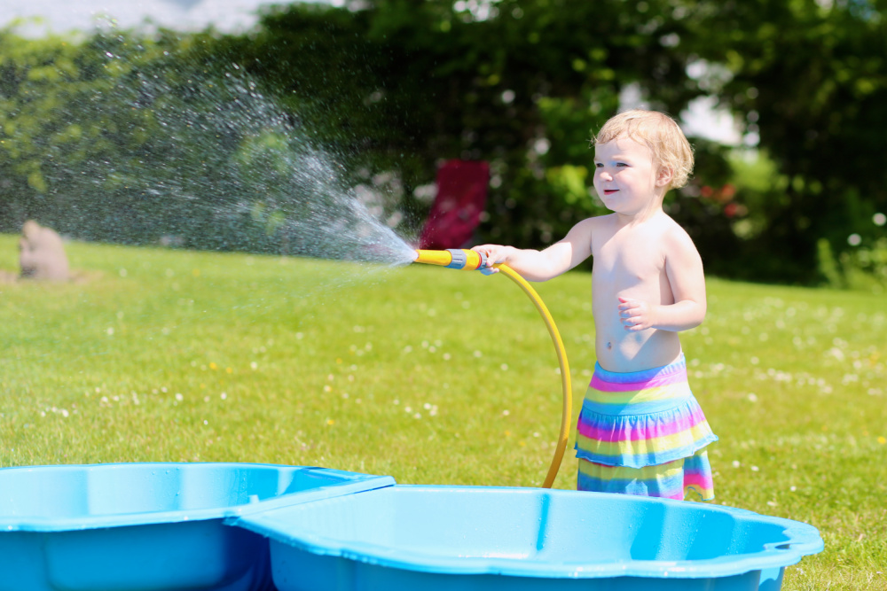 toddler playing with garden hose