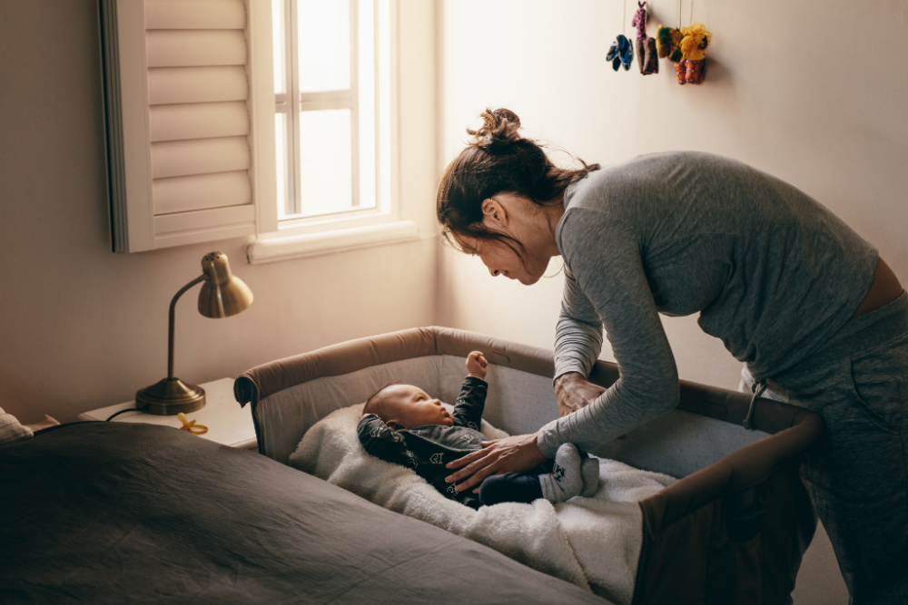 mom putting baby to sleep in bassinet