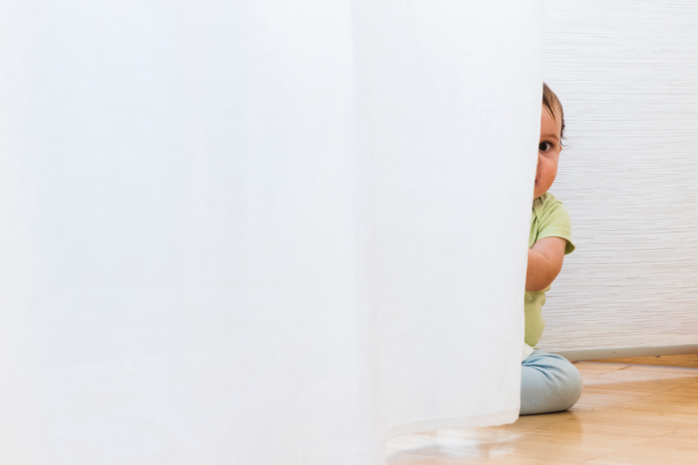 baby playing and hiding with white curtains