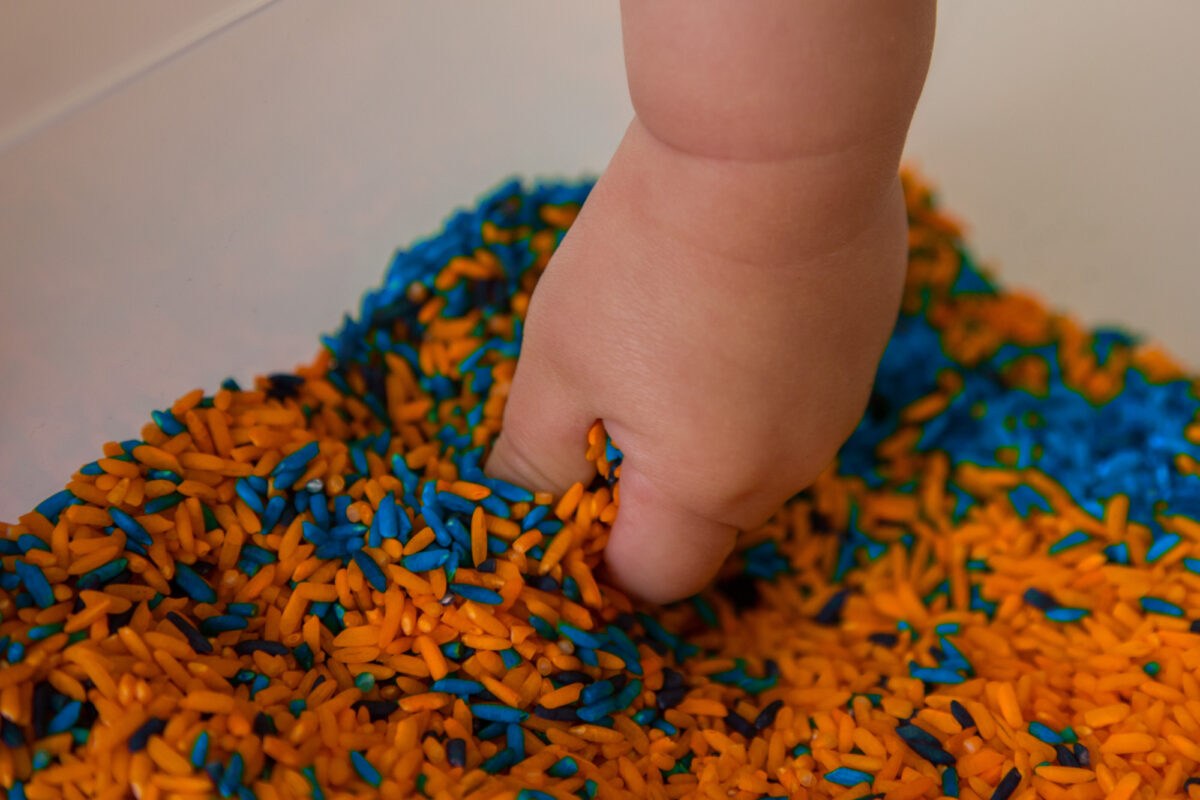 toddler playing with coloured rice