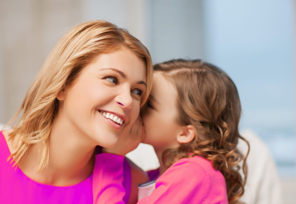 child whispering to mom