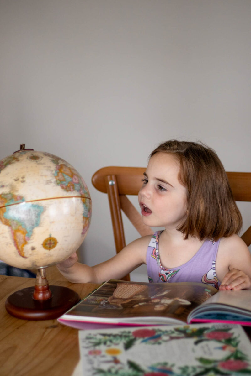 young girl looking at globe