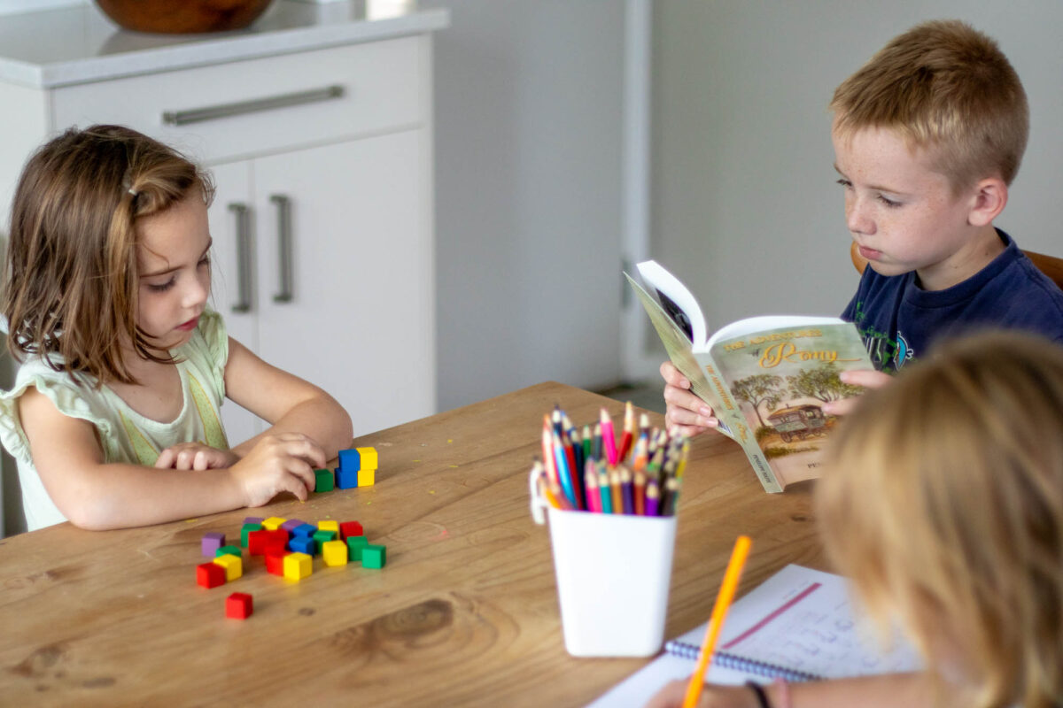 three kids doing homeschool work