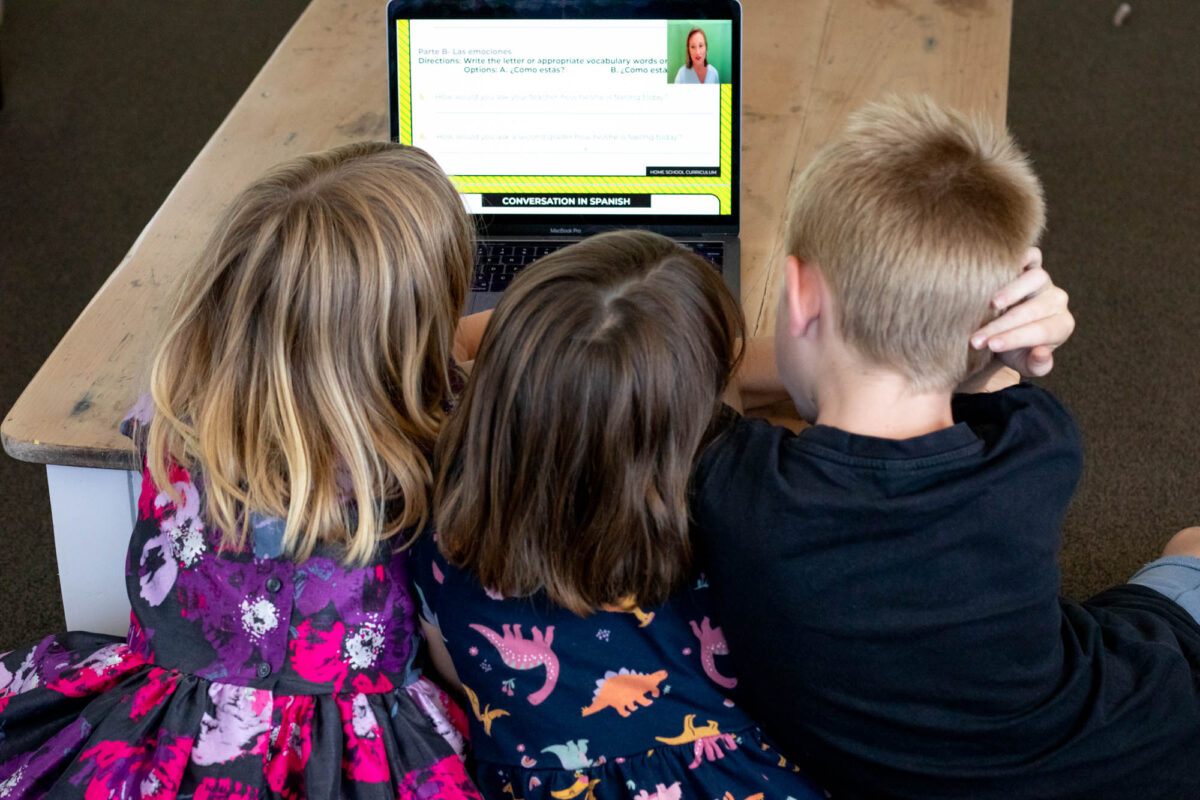 three kids watching homeschool spanish program