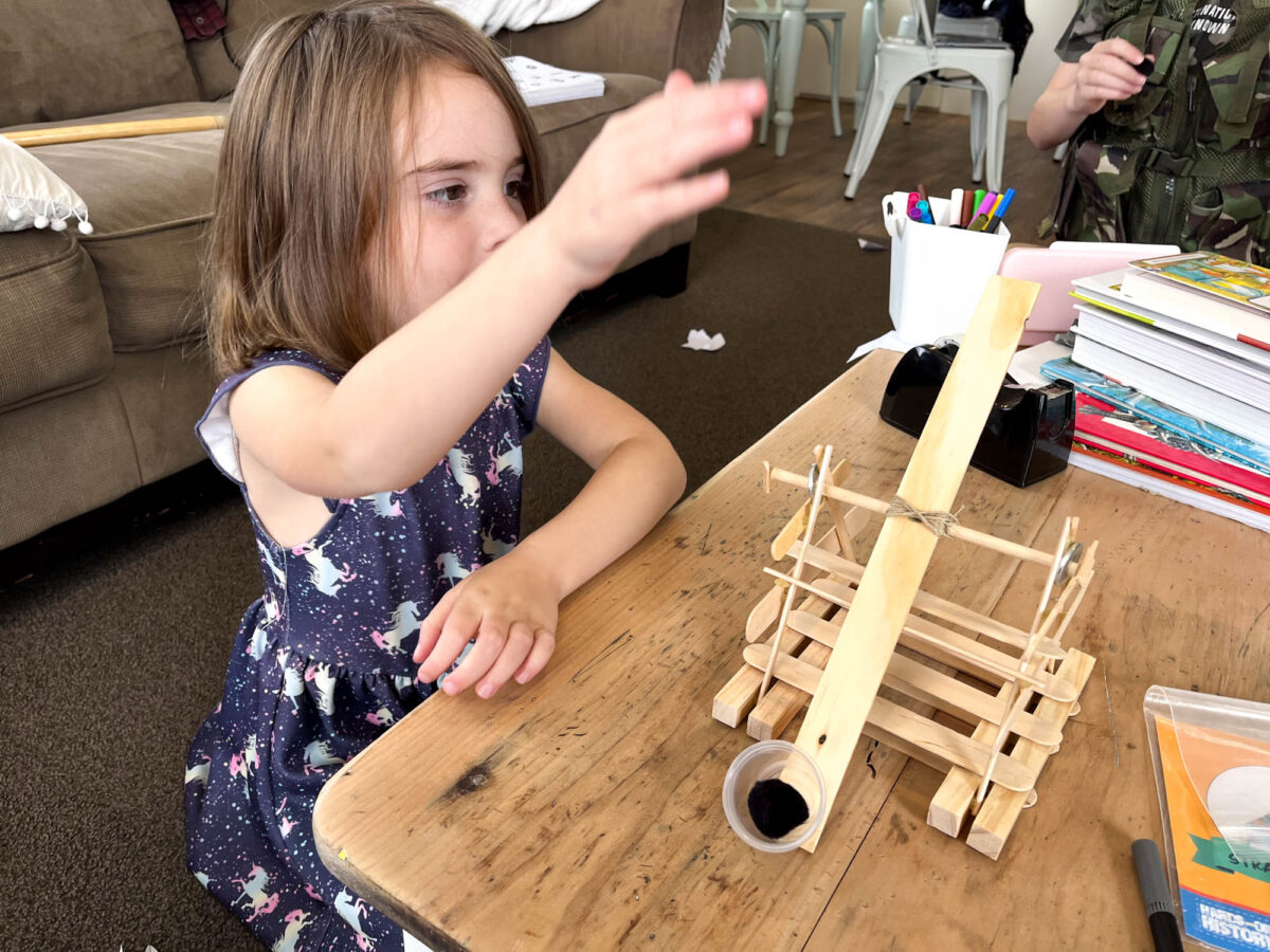 child trying out a homemade catapult