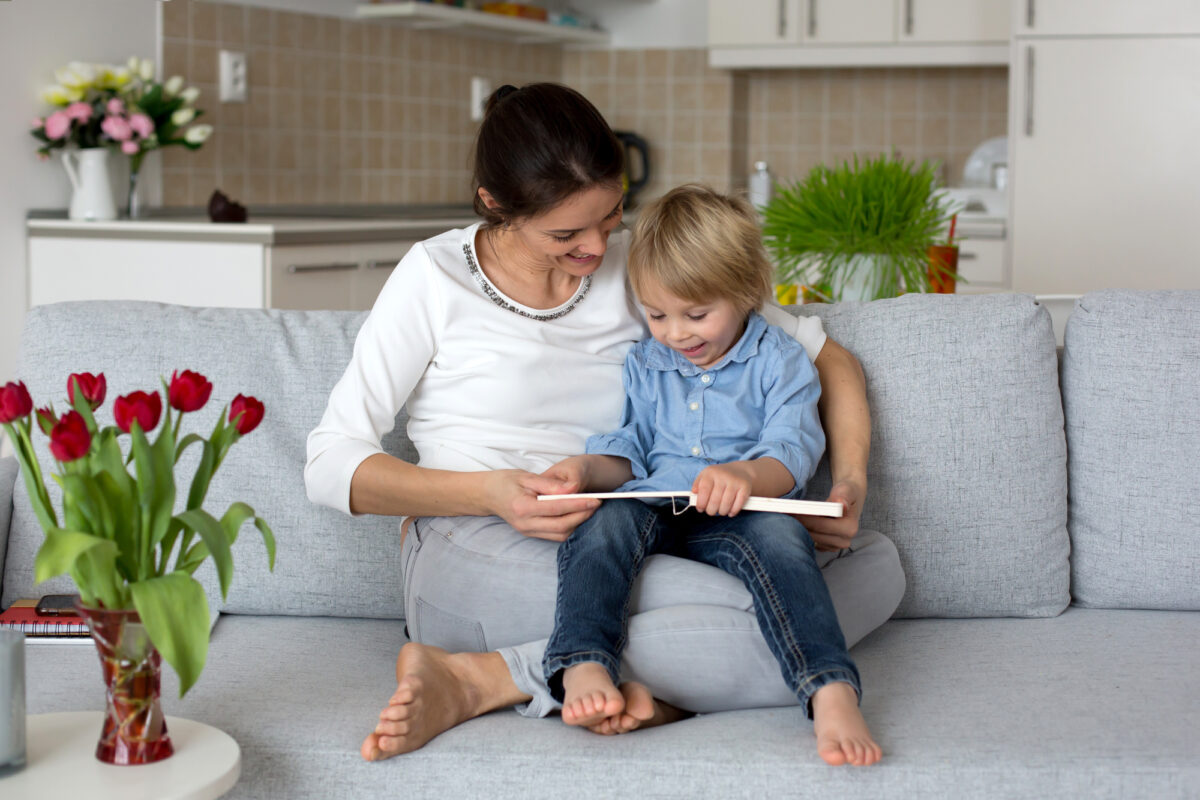 mom reading to preschooler son on a sofa