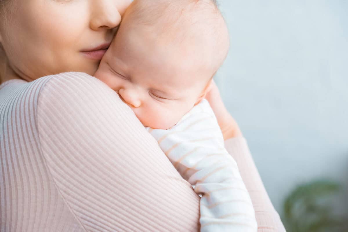 three week old newborn sleeping on mom