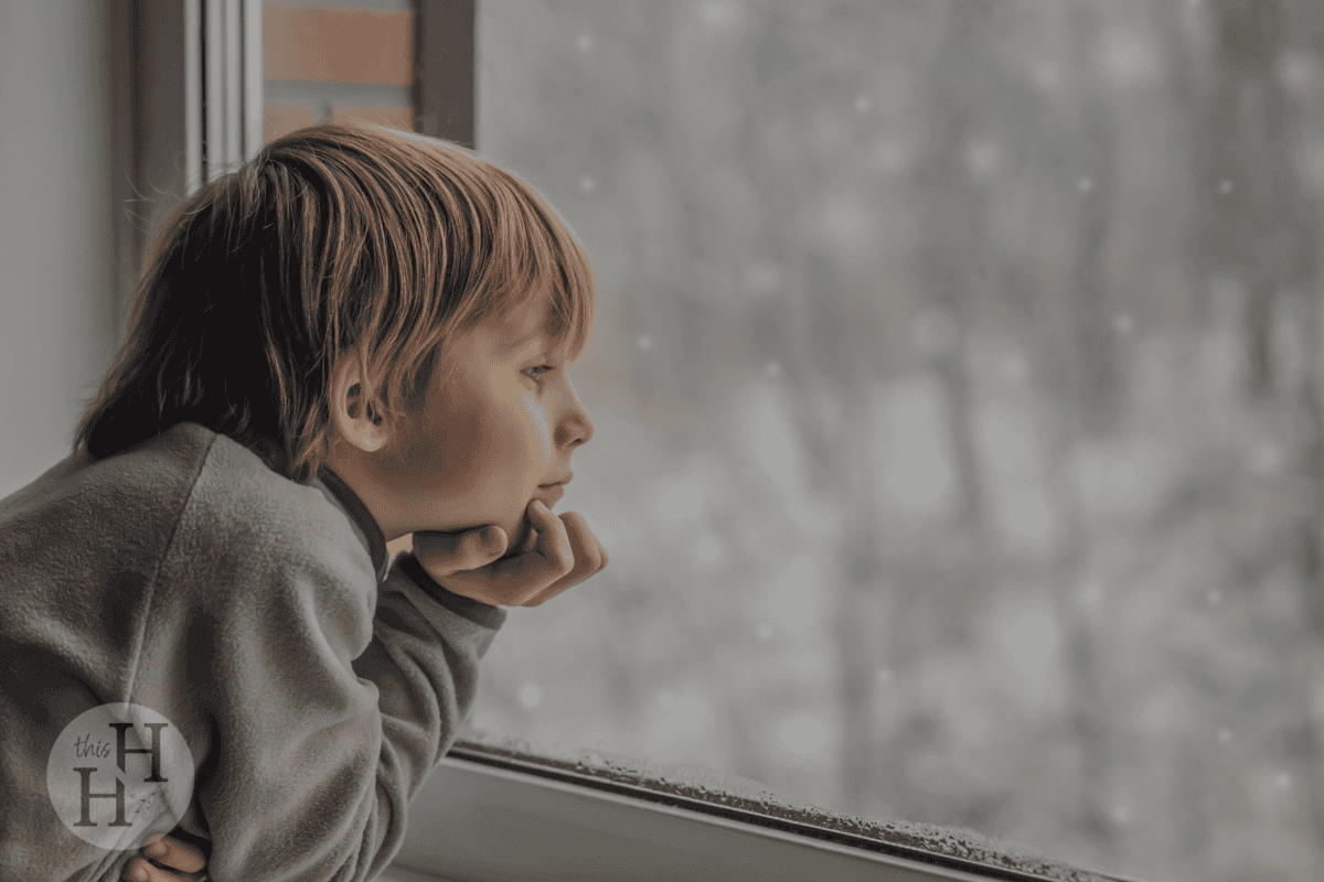 boy looking at the snow from the window