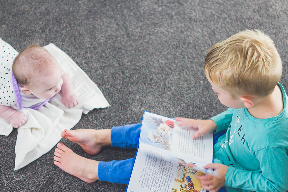 Brother reading to 5 month old sister