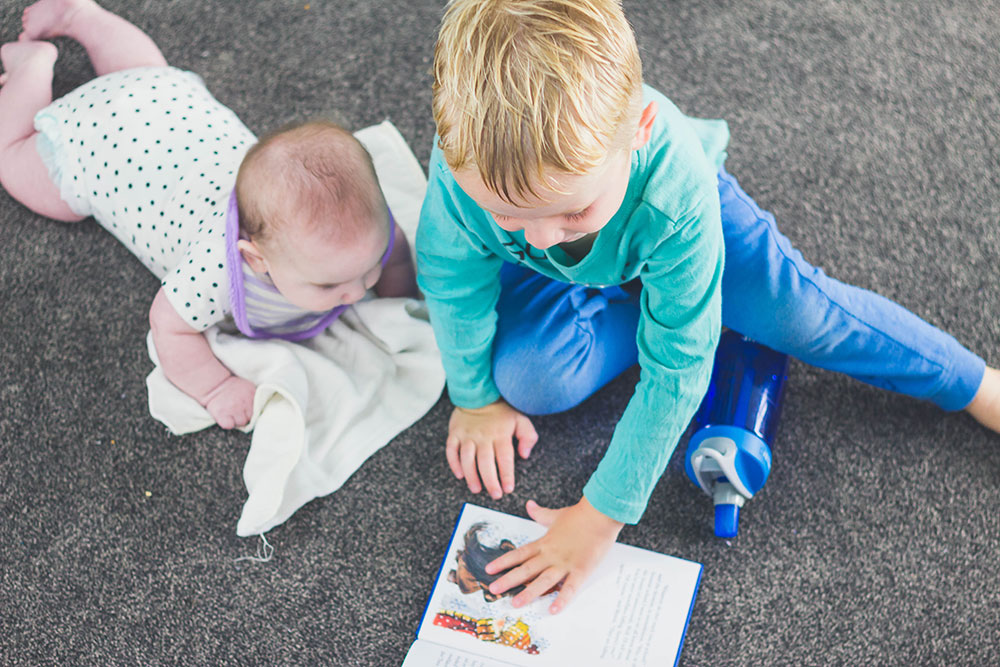 Preschooler reading to 5 month old baby