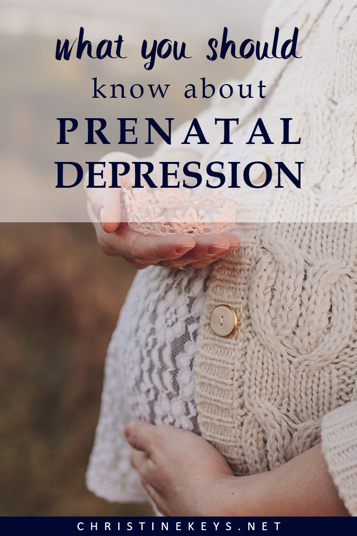 Pregnant woman holding pink baby crown
