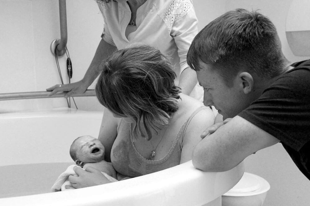 Mother holding baby in a birth pool